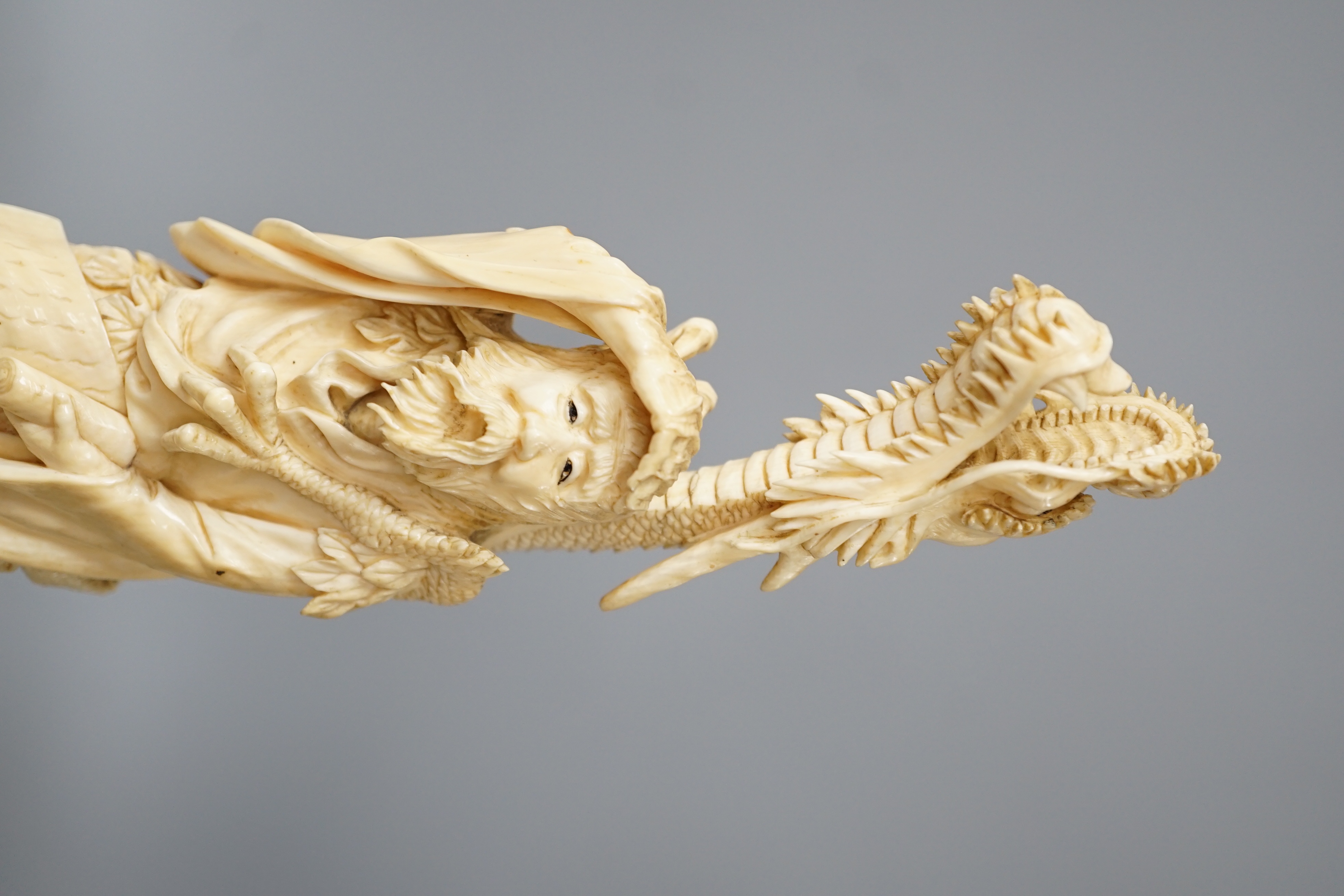 A Japanese ivory okimono of Shoshi Sennin and a dragon, early 20th century, signed, associated wood stand, 24cm excl stand